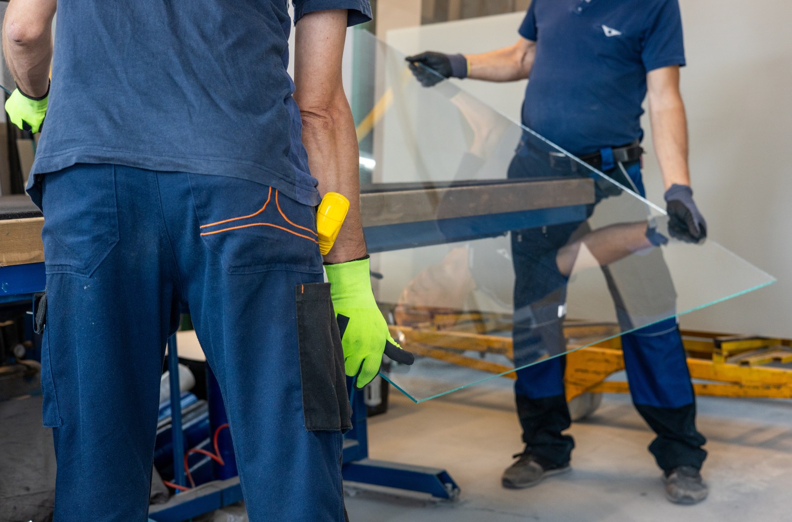 Two workers carrying a glass pane across the factory floor